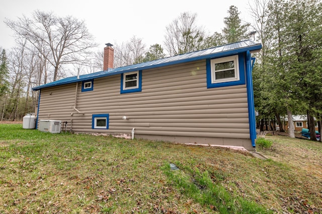 114 Smith Rd, Hudson, ME 04449 - view of property exterior featuring a chimney, central air condition unit, a yard, and metal roof