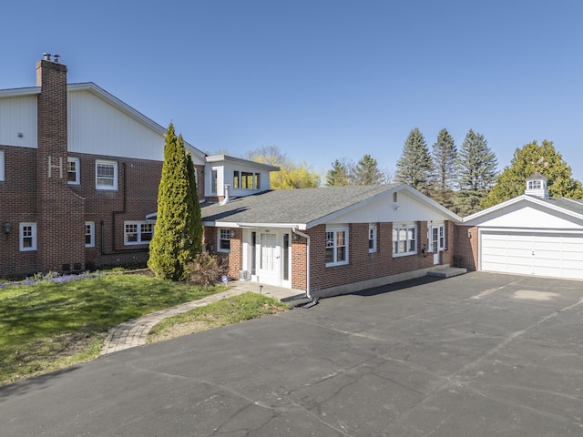 view of front of property featuring a chimney, an outdoor structure, brick siding, and a front lawn