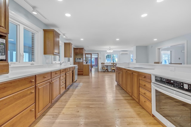 kitchen featuring light wood-style flooring, recessed lighting, brown cabinetry, light countertops, and appliances with stainless steel finishes