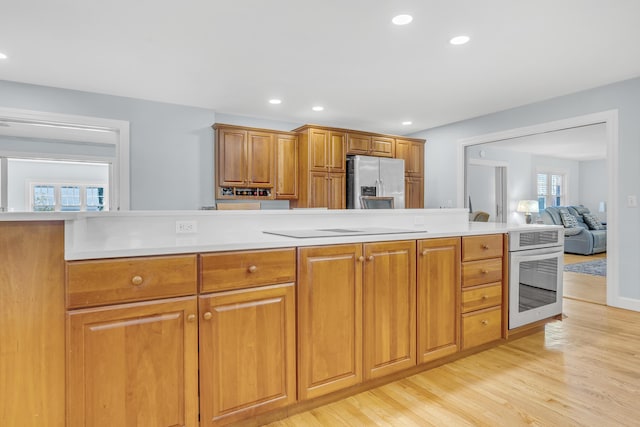 kitchen with brown cabinetry, recessed lighting, light wood-style flooring, light countertops, and appliances with stainless steel finishes