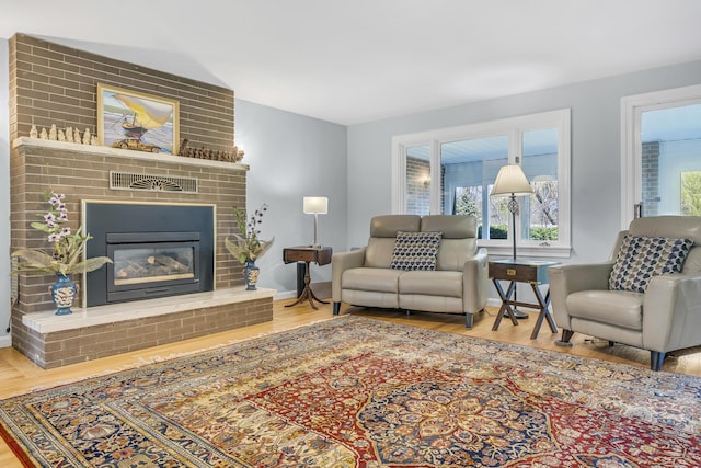 living room featuring baseboards, wood finished floors, a fireplace, and visible vents