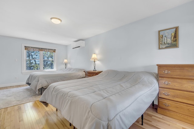bedroom with an AC wall unit, baseboards, and wood finished floors