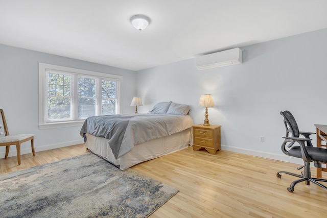 bedroom with baseboards, a wall mounted AC, and wood finished floors