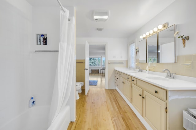 bathroom featuring a sink, double vanity, tile walls, and visible vents
