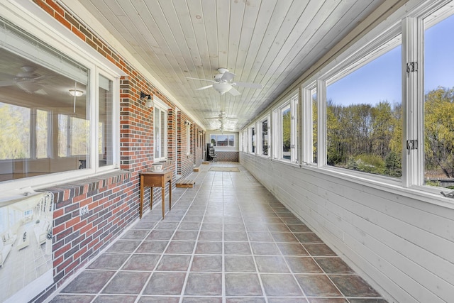 unfurnished sunroom with ceiling fan and plenty of natural light