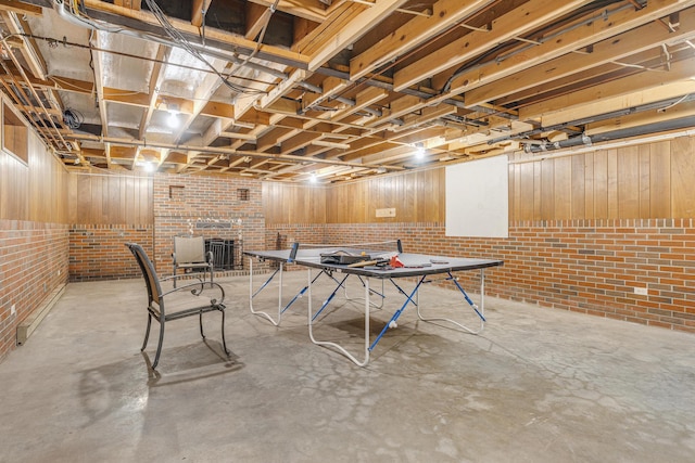 recreation room with unfinished concrete flooring and brick wall