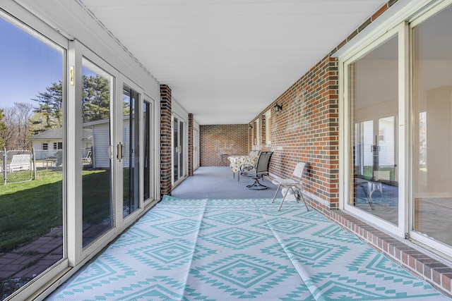 unfurnished sunroom with brick wall and carpet flooring
