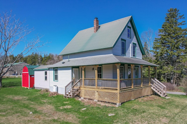 view of front of house with a porch, stairway, a front lawn, and a chimney