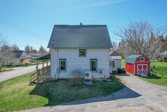back of property with a yard, metal roof, an outbuilding, and a shed