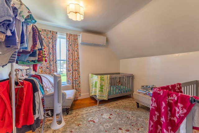 bedroom with an AC wall unit, lofted ceiling, and wood finished floors