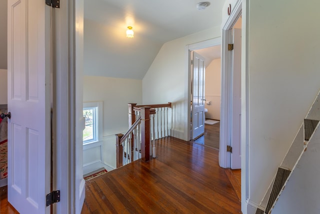 hall with wood finished floors, lofted ceiling, and an upstairs landing