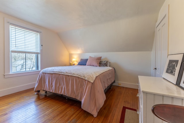 bedroom featuring baseboards, vaulted ceiling, and hardwood / wood-style flooring