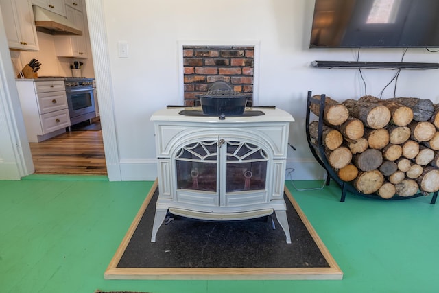 room details featuring baseboards, under cabinet range hood, wood finished floors, and stainless steel stove