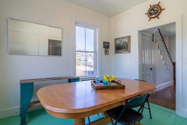 dining space with stairs, baseboards, and wood finished floors