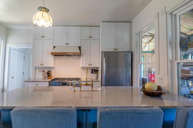 kitchen with white cabinets, freestanding refrigerator, wall chimney exhaust hood, and range