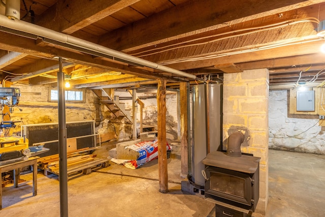 below grade area featuring water heater, electric panel, a wood stove, and stairs
