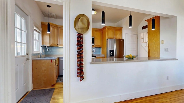 25 Nevens St Unit 1, Portland, ME 04103 - kitchen with stainless steel appliances, a sink, light wood-type flooring, backsplash, and light countertops