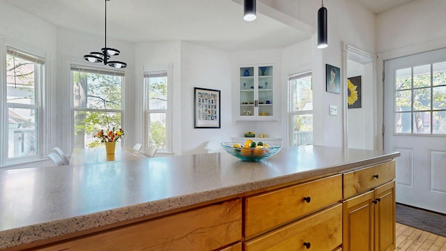 25 Nevens St Unit 1, Portland, ME 04103 - kitchen featuring a chandelier, pendant lighting, brown cabinets, light wood-type flooring, and light stone countertops