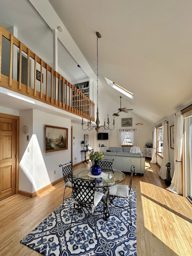 living area with high vaulted ceiling, baseboards, a ceiling fan, and light wood-style flooring