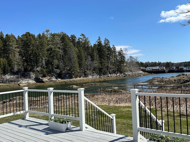 deck with a water view and a yard