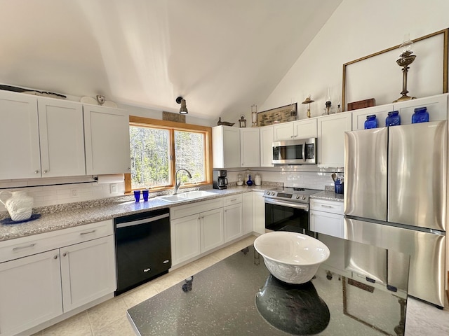 kitchen with white cabinets, light stone countertops, a sink, stainless steel appliances, and tasteful backsplash