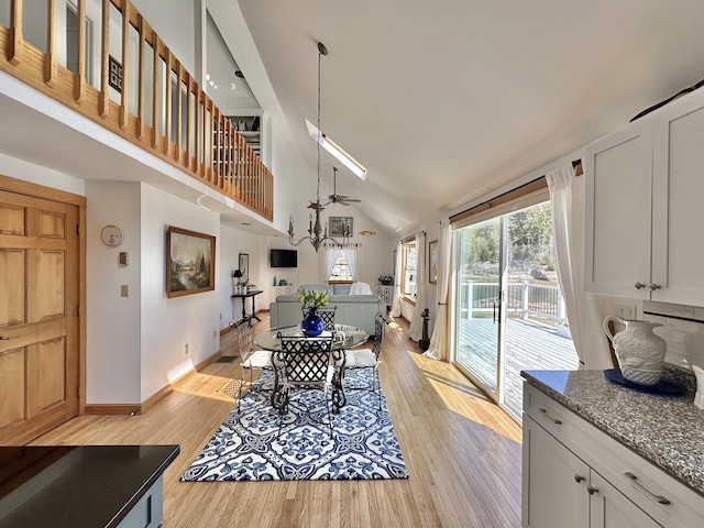 dining space featuring baseboards, high vaulted ceiling, and light wood-style flooring