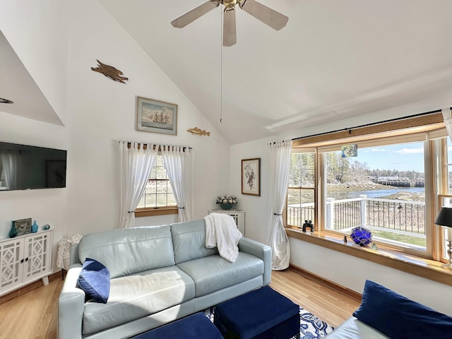 living room with ceiling fan, light wood-type flooring, high vaulted ceiling, baseboards, and a water view