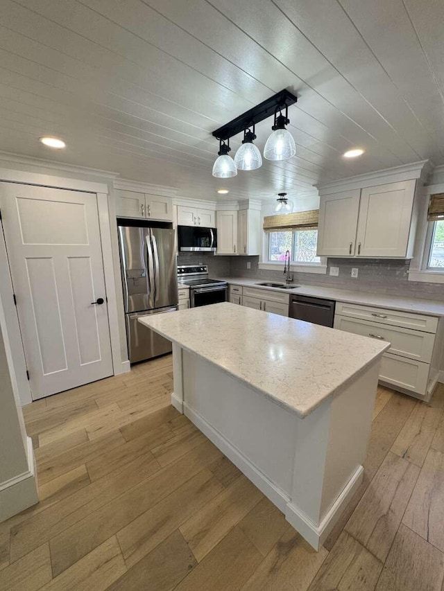 kitchen featuring a kitchen island, appliances with stainless steel finishes, a sink, white cabinets, and light wood-style floors