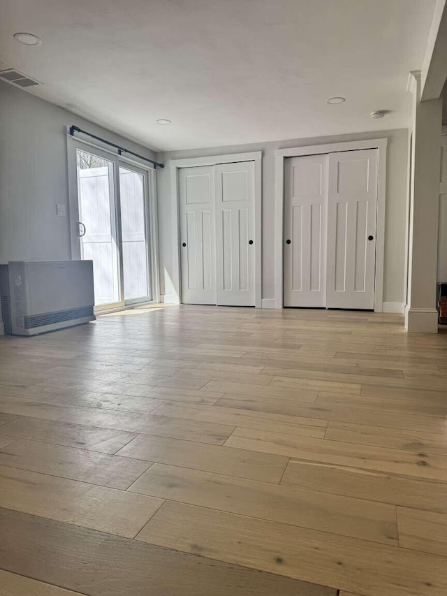 unfurnished bedroom featuring visible vents, two closets, access to exterior, light wood-style floors, and recessed lighting