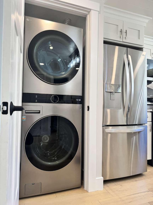 laundry area featuring light wood-style floors, laundry area, and stacked washer / drying machine