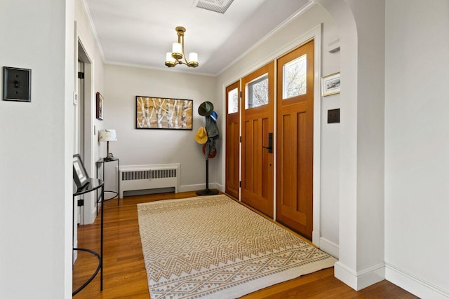 69 Brookside Rd, Portland, ME 04103 - foyer entrance featuring radiator heating unit, wood finished floors, a chandelier, arched walkways, and baseboards