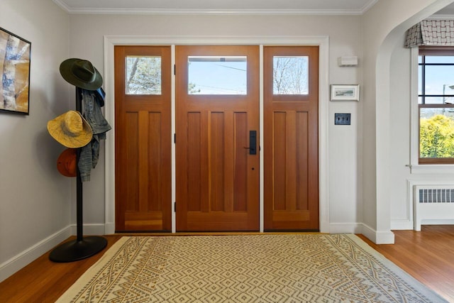 69 Brookside Rd, Portland, ME 04103 - entrance foyer with light wood-type flooring, baseboards, radiator, arched walkways, and crown molding
