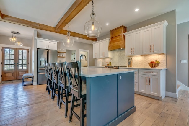 27 Oak Ridge Ter, Arundel, ME 04046 - kitchen with stainless steel fridge with ice dispenser, light wood-style flooring, beam ceiling, custom exhaust hood, and light countertops