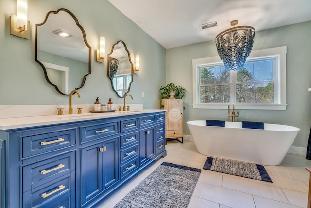 27 Oak Ridge Ter, Arundel, ME 04046 - bathroom featuring a chandelier, double vanity, a freestanding tub, and tile patterned flooring