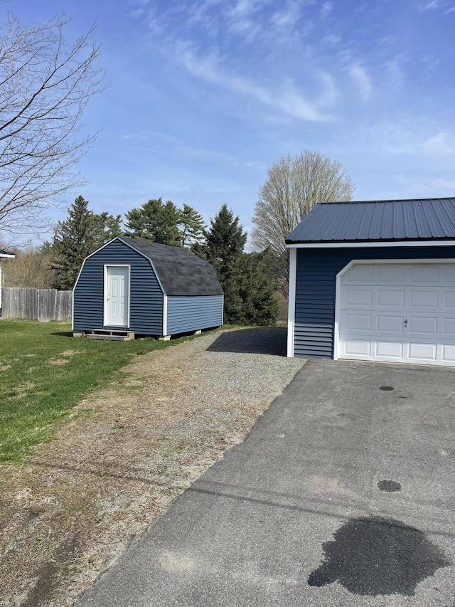 garage featuring fence and a shed