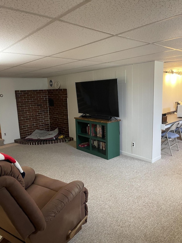 living area featuring baseboards, a drop ceiling, and carpet flooring