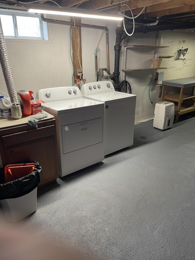 clothes washing area featuring washing machine and clothes dryer and cabinet space