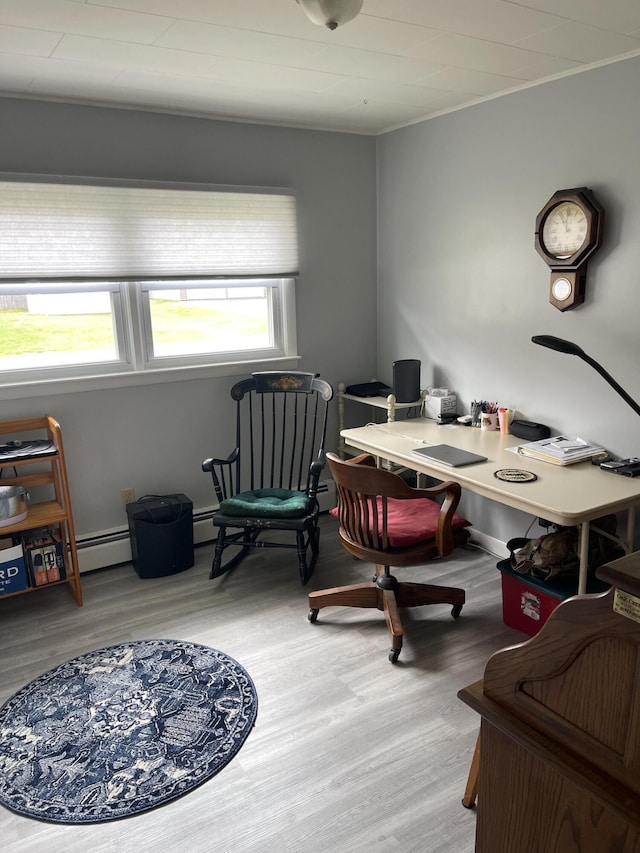 home office with a baseboard heating unit, a wealth of natural light, and wood finished floors