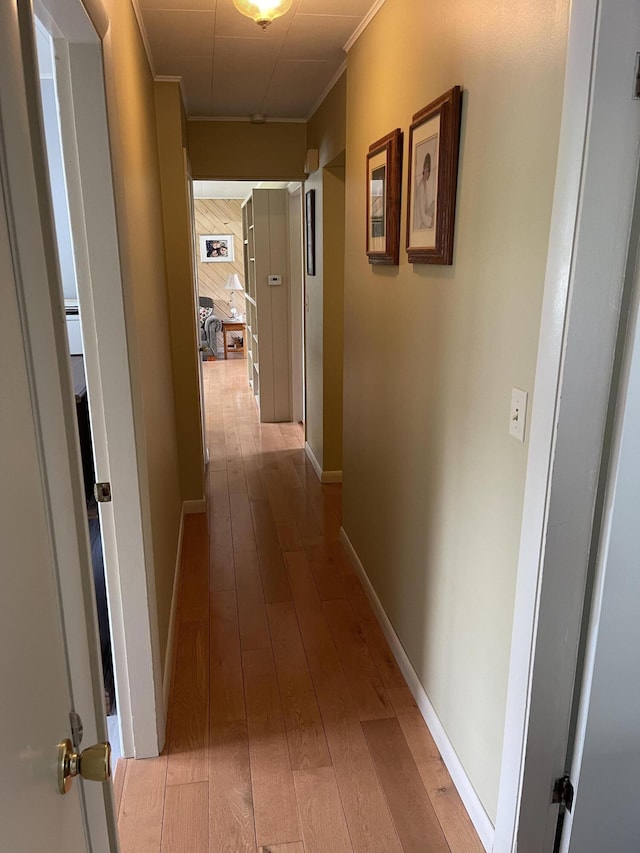 hallway with baseboards, ornamental molding, and hardwood / wood-style flooring