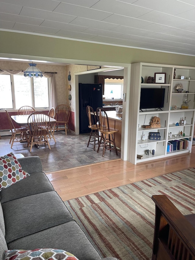 living room with crown molding, a baseboard radiator, a healthy amount of sunlight, and wood finished floors