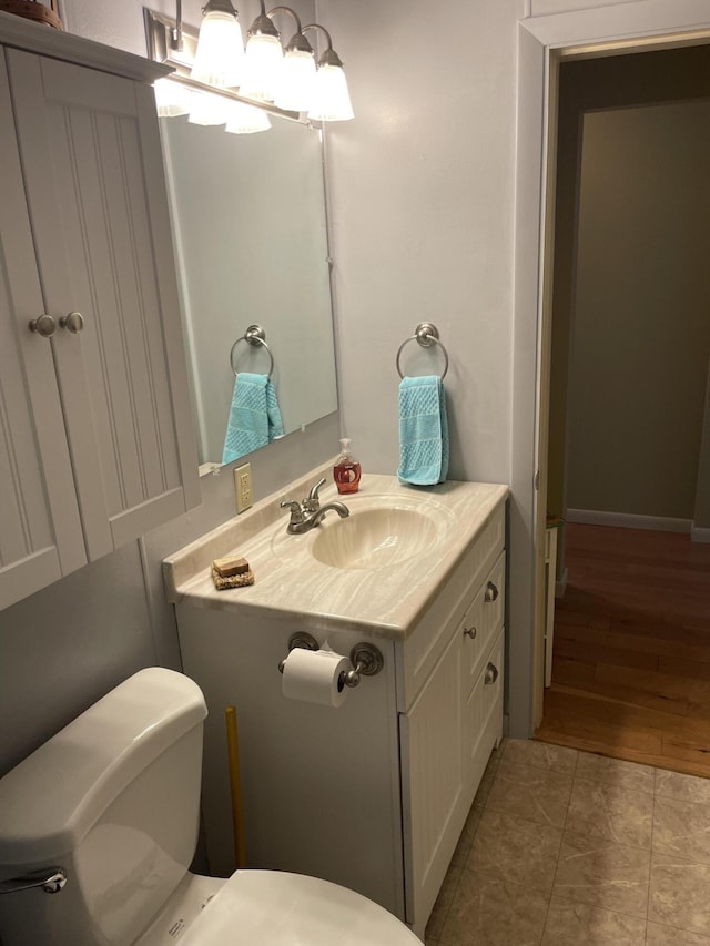 half bath featuring vanity, toilet, and wood finished floors