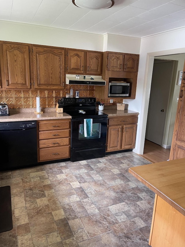 kitchen featuring under cabinet range hood, brown cabinetry, decorative backsplash, black appliances, and light countertops