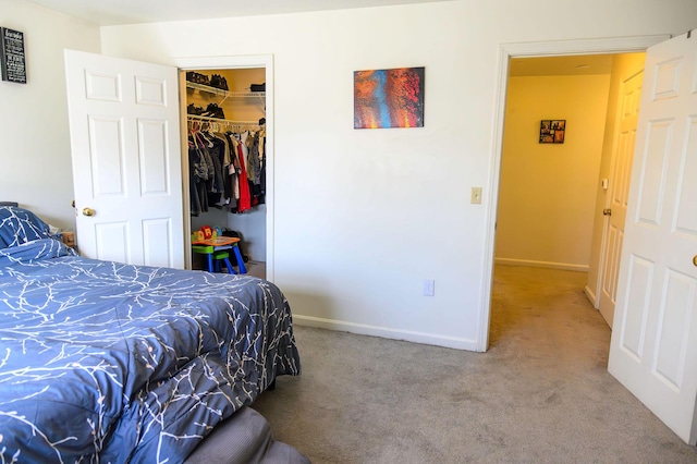 carpeted bedroom featuring baseboards, a spacious closet, and a closet