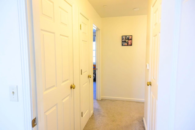 hall featuring baseboards and light carpet