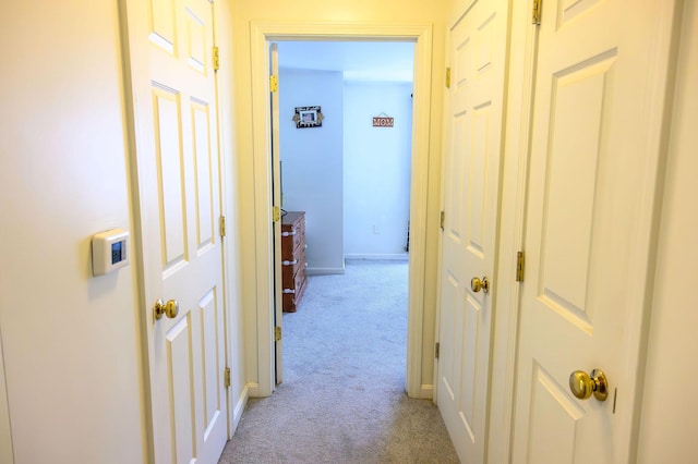 hallway featuring baseboards and light carpet