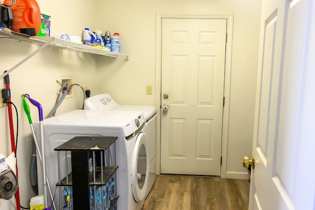 clothes washing area with washer and dryer, laundry area, and wood finished floors