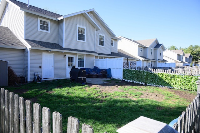 rear view of property featuring a yard and a fenced backyard