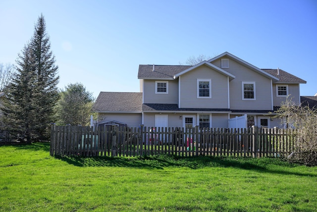 rear view of house with a shingled roof, a yard, and fence private yard