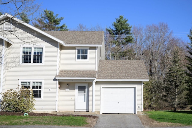 traditional-style home featuring a garage, roof with shingles, and driveway