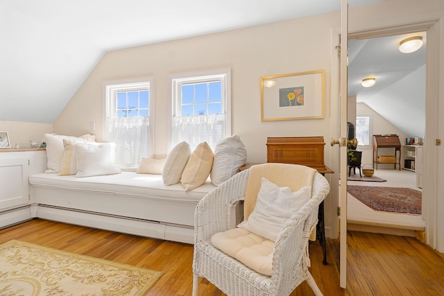 bedroom with vaulted ceiling, a baseboard radiator, and light wood-type flooring